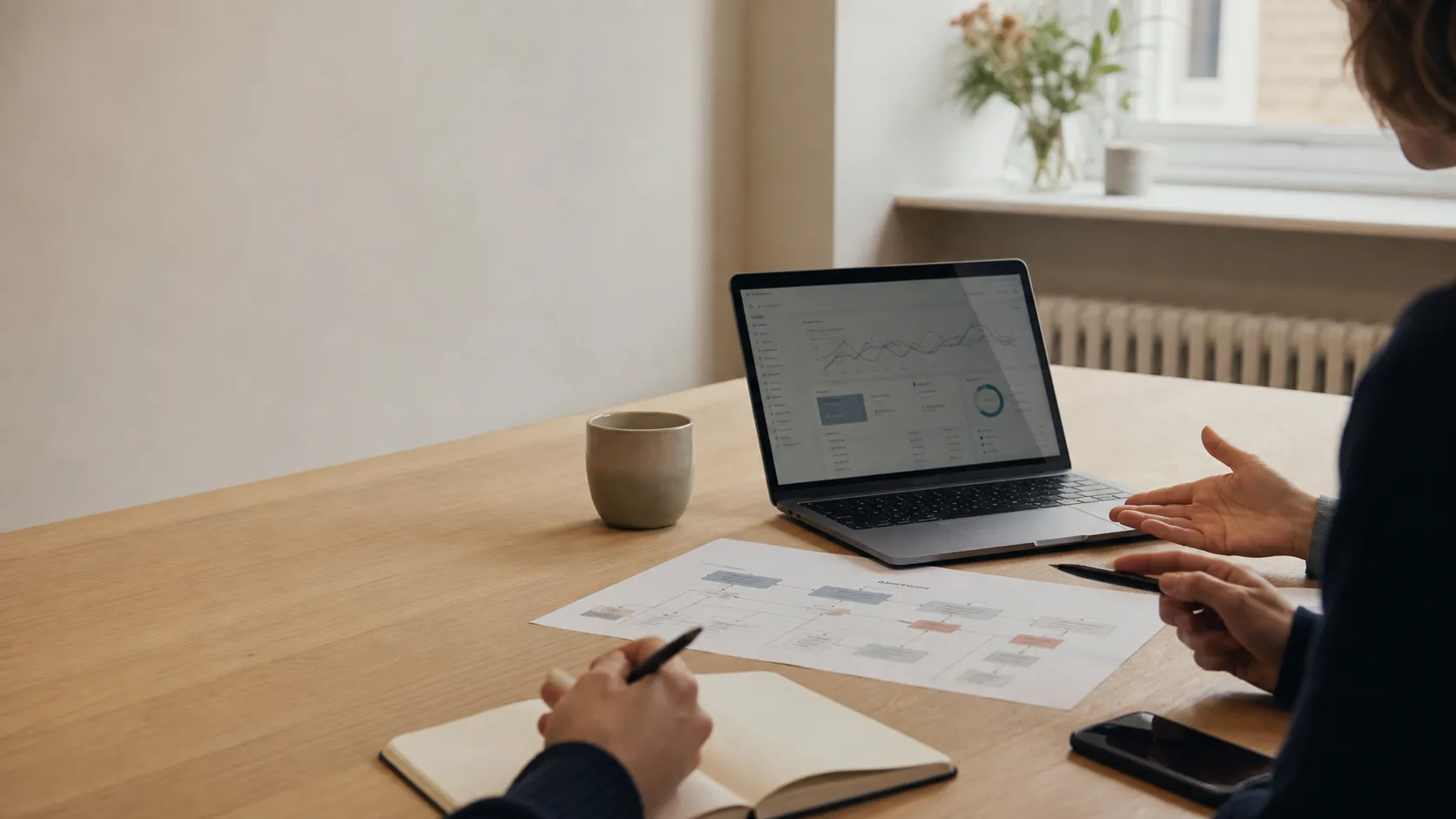 A laptop showing performance data beside a printed customer journey diagram.